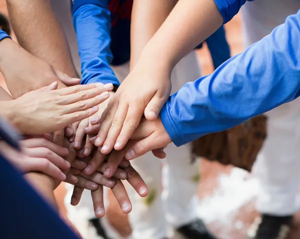 A group of people stacking their hands together in a team gesture.