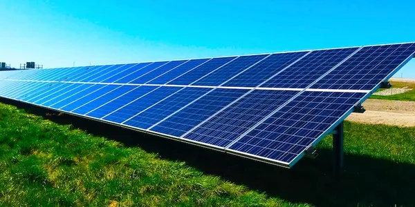 Solar panels installed on a grassy field under a clear blue sky.