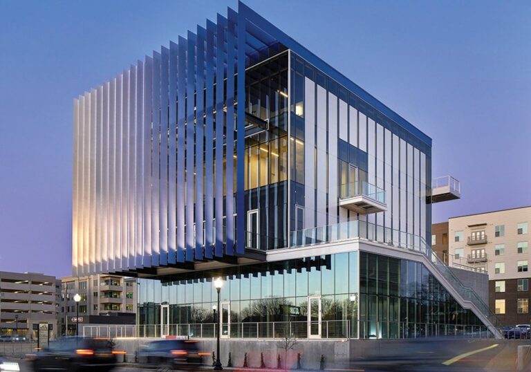 Exterior of the modern Hotel Revel building at dusk, featuring vertical metal slats and glass windows with a sleek design.